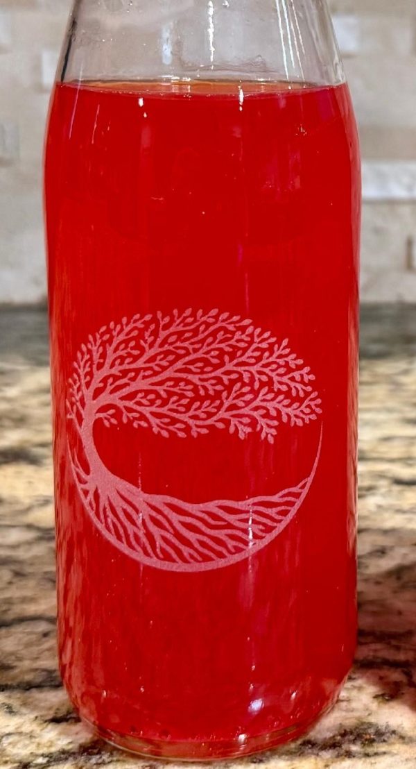 Custom etched glass bottles with laser engraved corporate logo used as a wedding centerpiece.