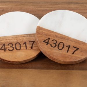 Personalized white marble and wood round coasters engraved with custom zip code for housewarming gift.