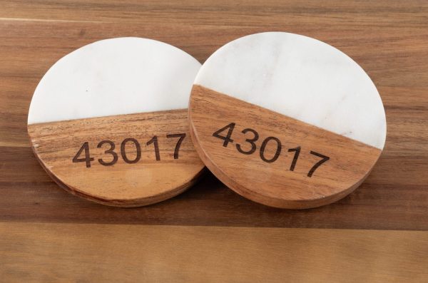 Personalized white marble and wood round coasters engraved with custom zip code for housewarming gift.