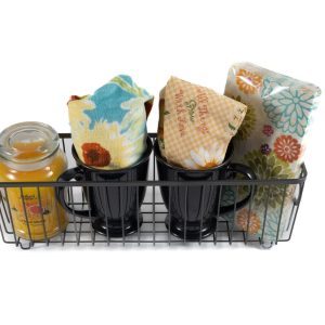 Housewarming gift basket with mugs candle and kitchen towels in a wire basket.