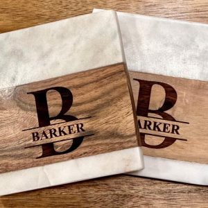 Personalized marble and wood square coasters with custom family name engraving.