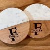 Pair of personalized marble and wood coasters with laser-engraved family name and monogram for a housewarming gift.