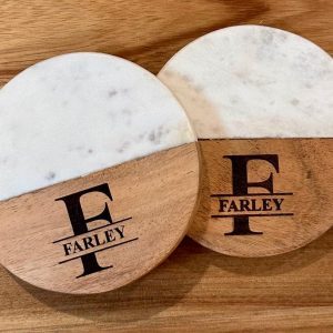 Pair of personalized marble and wood coasters with laser-engraved family name and monogram for a housewarming gift.