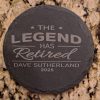 Pair of round black slate coasters laser engraved with The Legend Has Retired and personalized name and date.
