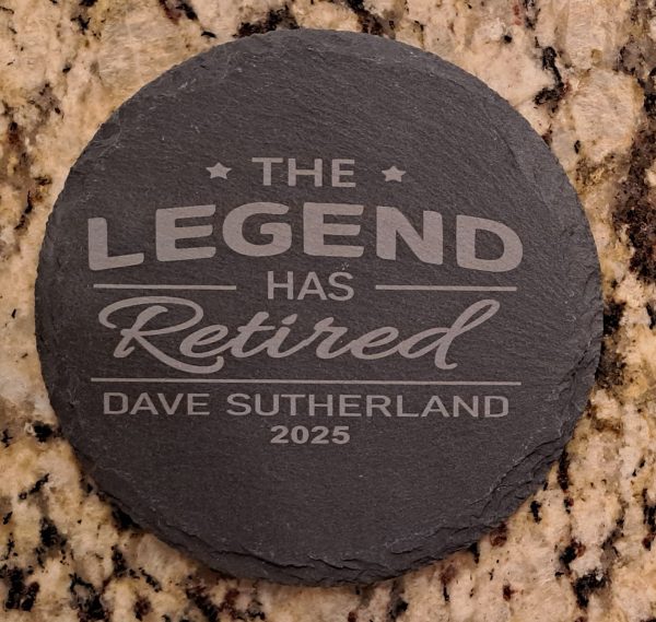 Pair of round black slate coasters laser engraved with The Legend Has Retired and personalized name and date.