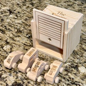 Personalized wooden kids garage with engraved family names for toy car storage.