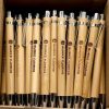 50 custom laser engraved wooden pens with company logo displayed on a professional desk.